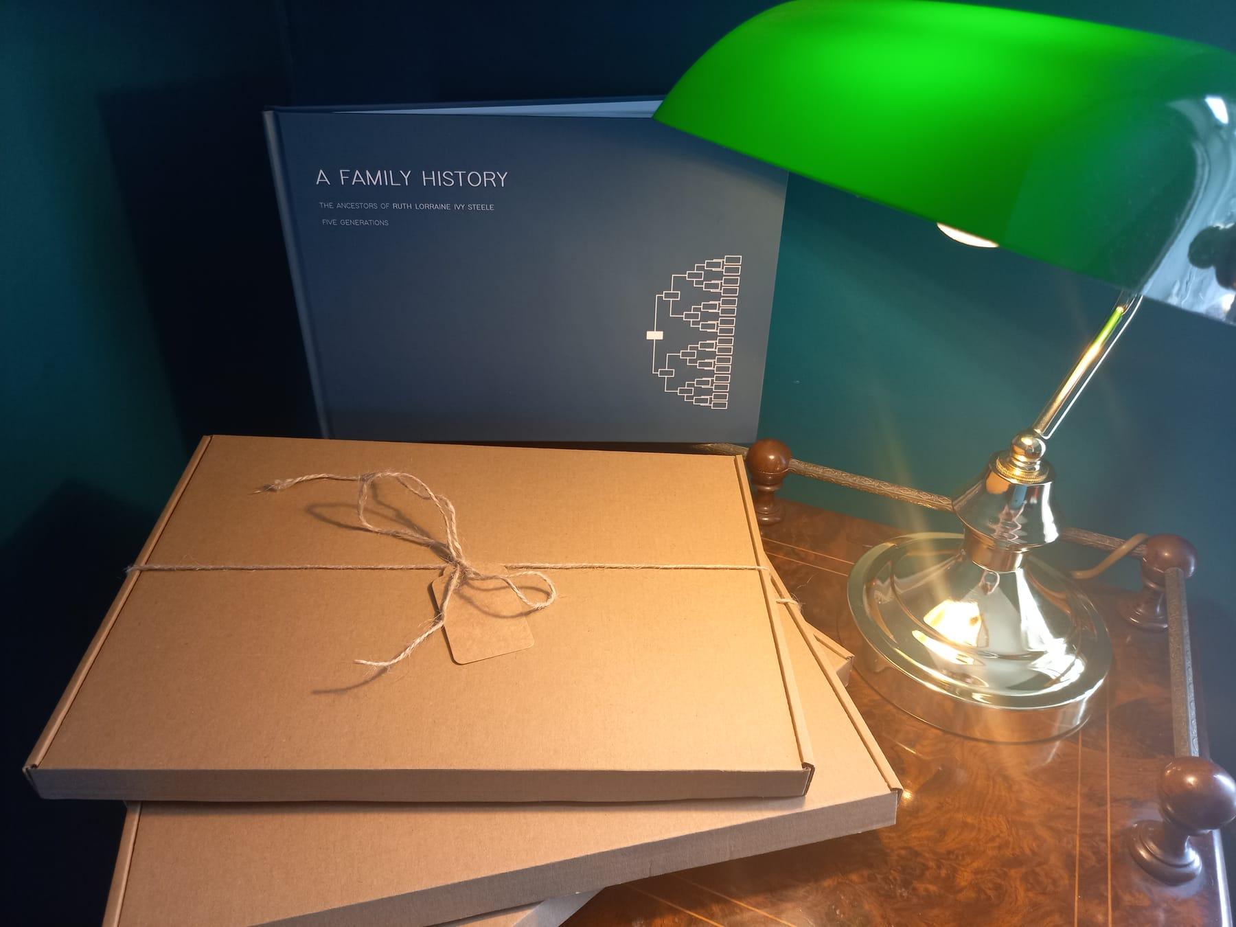 A boxed family history book tied with twine, under a green banker's lamp