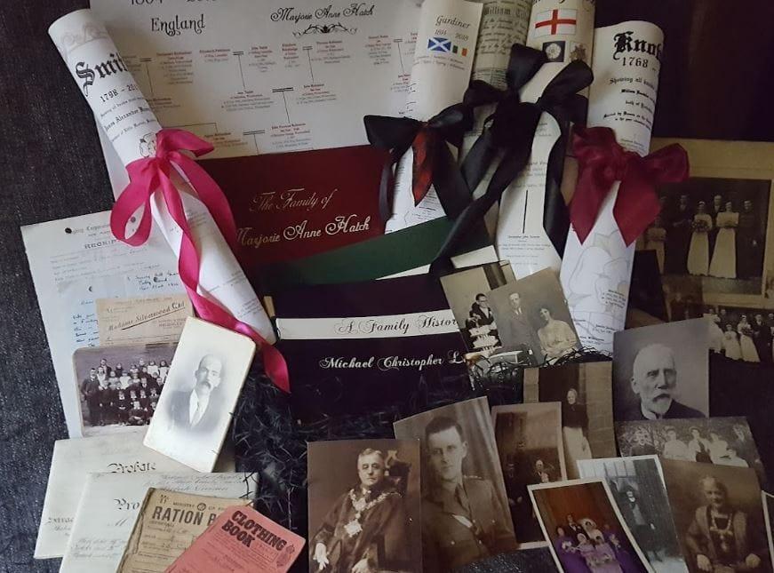 Family history books and scrolls tied with ribbons, among old family photographs
