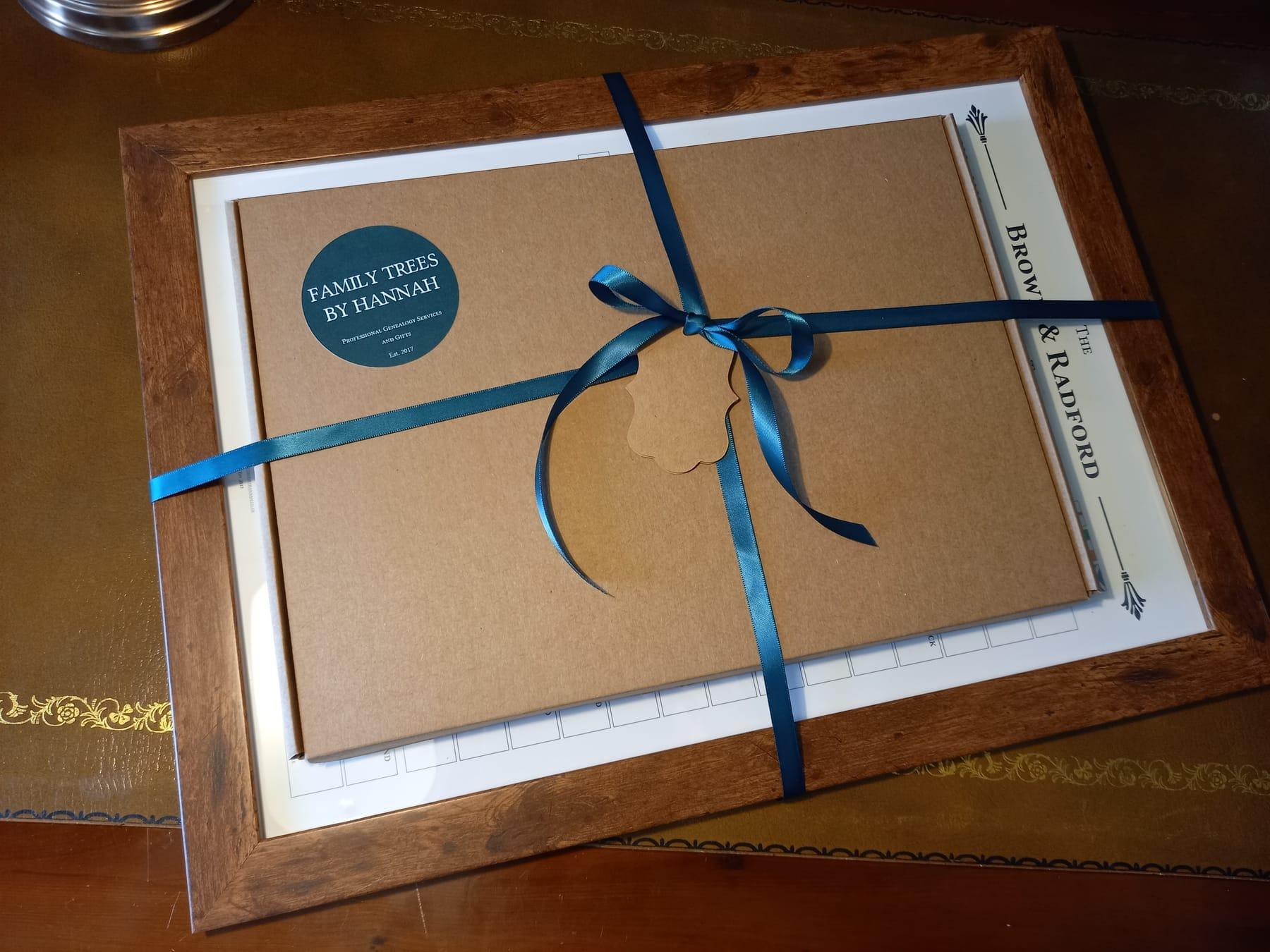 A framed family tree wrapped in brown paper and tied with a blue ribbon